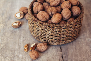 Walnuts in a round wicker basket on a wooden background. Top view. Copy, empty space for text