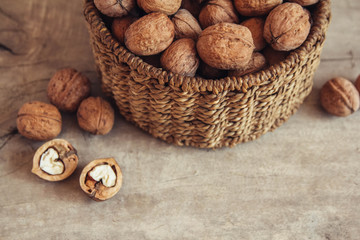 Walnuts in a round wicker basket on a wooden background. Top view. Copy, empty space for text