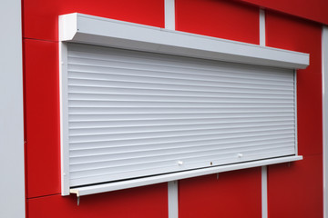 White roller shutters at a red kiosk. Street retail, shop, market. Modern safety and security.