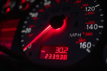 car dashboard. Speedometer with red backlight at night close up