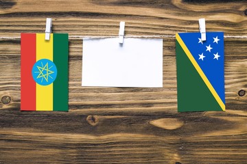 Hanging flags of Ethiopia and Solomon Islands attached to rope with clothes pins with copy space on...