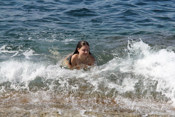 A girl swims in the sea off the coast