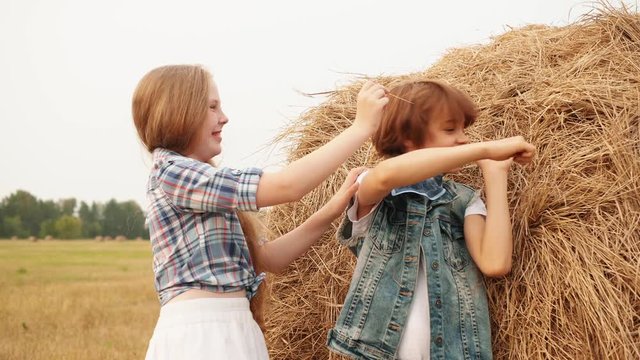 Cute happy boy and girl playing with hay in field. Adorable cheerful teenage girl and boy having fun near haystack in rural area