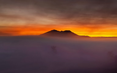 view morning of Peak mountain around with sea of fog with red sun light in cloudy sky background, sunrise at Thung Salang Luang, Khao Kho, Phetchabun, Thailand.