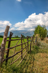 Fototapeta na wymiar A handmade wooden fence made of thin rods. The old fence of tree trunks, rural landscape, nature wallpaper background.