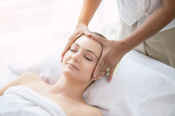 Fototapeta na wymiar Face massage. Attractive beautiful young woman relax lying on massage bed in spa salon. Spa aroma therapy and massage facial beauty treatment concept.