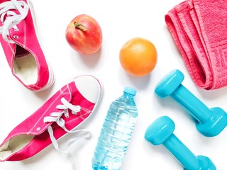 Red gumshoes, apple, orange, water bottle, dumbbells and towel. Flat lay fitness photo