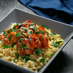 Israeli pearl couscous with shrimps in a square grey bowl.