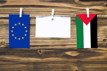 Hanging flags of European Union and Palestine attached to rope with clothes pins with copy space on...