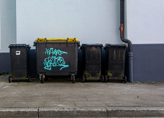 black plastic trash containers street by day closeup