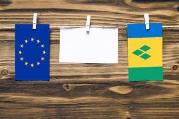 Hanging flags of European Union and Saint Vincent And The Grenadines attached to rope with clothes...