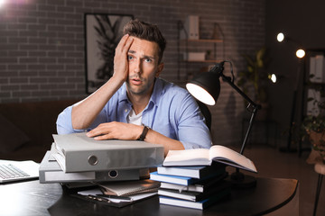 Tired man trying to meet deadline in office