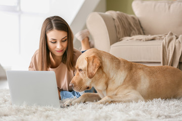 Beautiful young woman with cute dog using laptop at home © Pixel-Shot