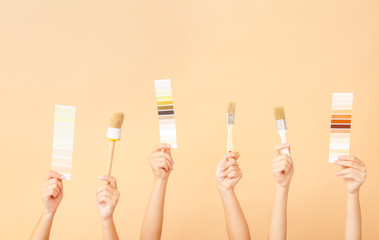 Female hands with painter's tools on color background