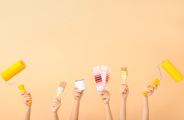 Female hands with painter's tools on color background