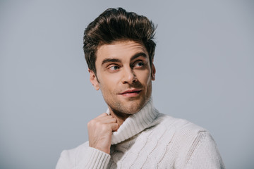 handsome stylish man posing in white knitted sweater, isolated on grey