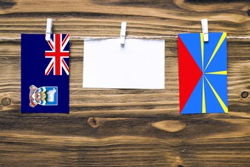 Hanging flags of Falkland Islands and Reunion attached to rope with clothes pins with copy space on...
