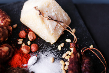 sausages with parmesan, citrus fruits and nuts on black background, top view