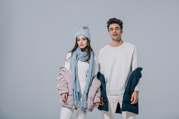 fashionable young couple posing in winter outfit, isolated on grey