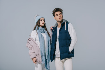 beautiful stylish couple posing in winter outfit, isolated on grey