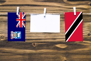 Hanging flags of Falkland Islands and Trinidad And Tobago attached to rope with clothes pins with...
