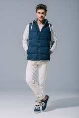 handsome fashionable man posing in waistcoat on grey