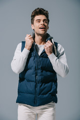 handsome smiling man posing in autumn waistcoat, isolated on grey