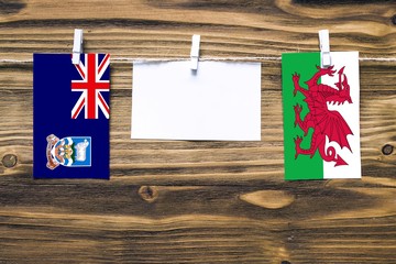 Hanging flags of Falkland Islands and Wales attached to rope with clothes pins with copy space on...