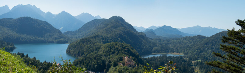 View of Bavaria countryside with rolling mountains, trees, and Lake Alpsee