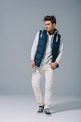 handsome trendy man posing in autumn waistcoat on grey