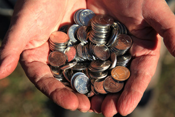 Handful or pile of silver coins in the old man hands. Concept of old age, retirement, saving and wealth