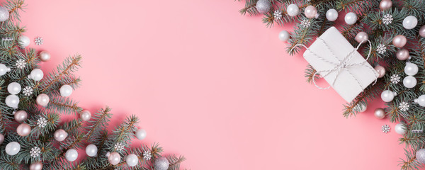 Christmas silver pink glass ball and fir branches on pink. Xmas banner with space for text. View from above.