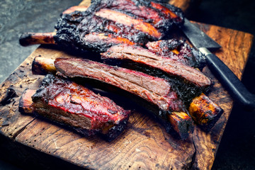 Barbecue burnt chuck beef ribs marinated with hot chili sauce sliced as closeup on an old rustic...