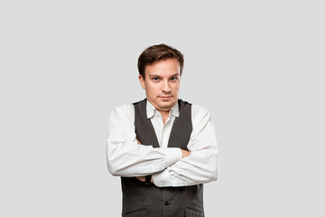 Young businessman in a white shirt and grey vest holding hand crossed.