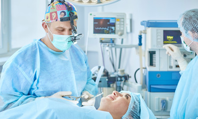 Several doctors surrounding patient on operation table during their work. Team surgeons at work in operating room