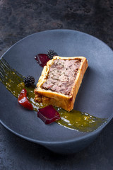 French pate en croute with goose liver, fruit relish and jelly as closeup on a modern design cast...
