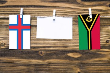 Hanging flags of Faroe Islands and Vanuatu attached to rope with clothes pins with copy space on...