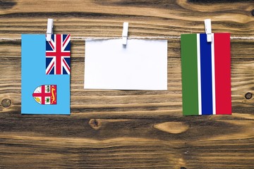 Hanging flags of Fiji and Gambia attached to rope with clothes pins with copy space on white note...