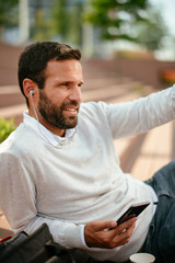 Fototapeta premium Young businessman listening music outdoors 
