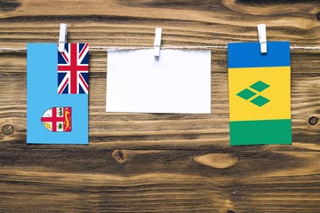 Hanging flags of Fiji and Saint Vincent And The Grenadines attached to rope with clothes pins with...