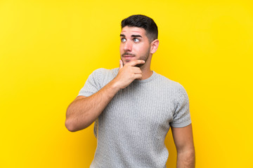 Young handsome man over isolated yellow background thinking an idea