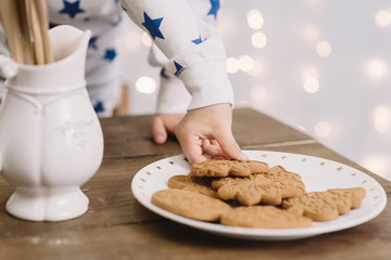 Child hand holding a gingerbread new year tree with Christmas lights on background. Festive bold bokeh