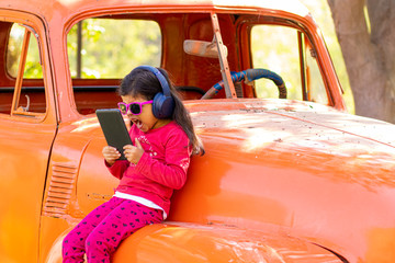 Naklejka premium Little girl listening to music on the tablet with her headphones in the truck car