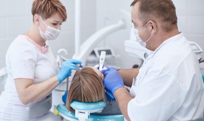 Fototapeta premium Doctor dentist treats teeth of a beautiful young girl patient. The girl on reception at the dentist. Doctor dentist treats tooth