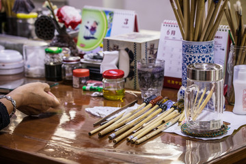 Chinese craftsman paints traditional pattern on porcelain vase.
