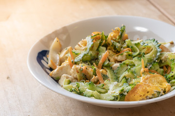 Stir-fried bitter melon and egg, the traditional food of Okinawa, Japan, contained in a white dish placed on wooden table