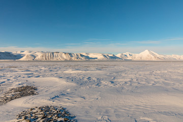 Arctic winter landscape with frozen fjord and snow covered mountains on Svalbard, Norway