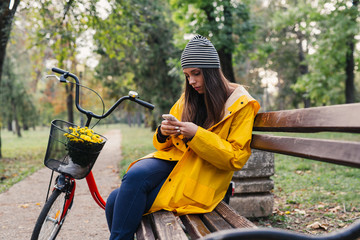 woman outdoor in park sitting bench using mobile phone