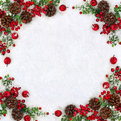 Christmas decoration. Frame of cones pine, twigs christmas tree, red berries and apples on snow with space for text. Top view, flat lay