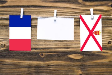 Hanging flags of France and Jersey attached to rope with clothes pins with copy space on white note...